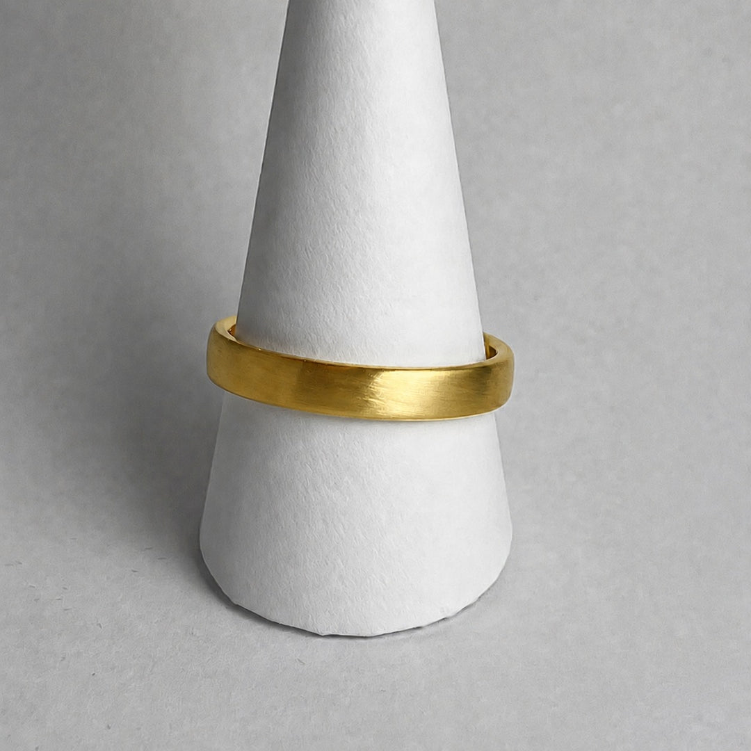 Single curved 18ct yellow gold wedding band with a matt finish on a ring cone