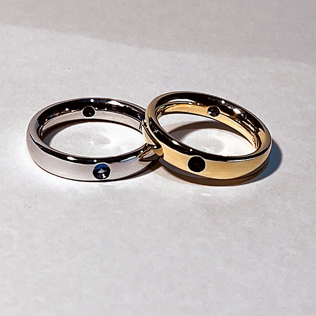 A pair of 18ct gold wedding rings set with an emerald and a tanzanite