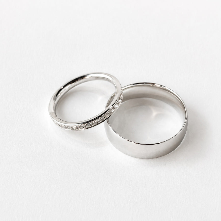 A platinum grain set diamond wedding ring beside a 9ct white gold court wedding band