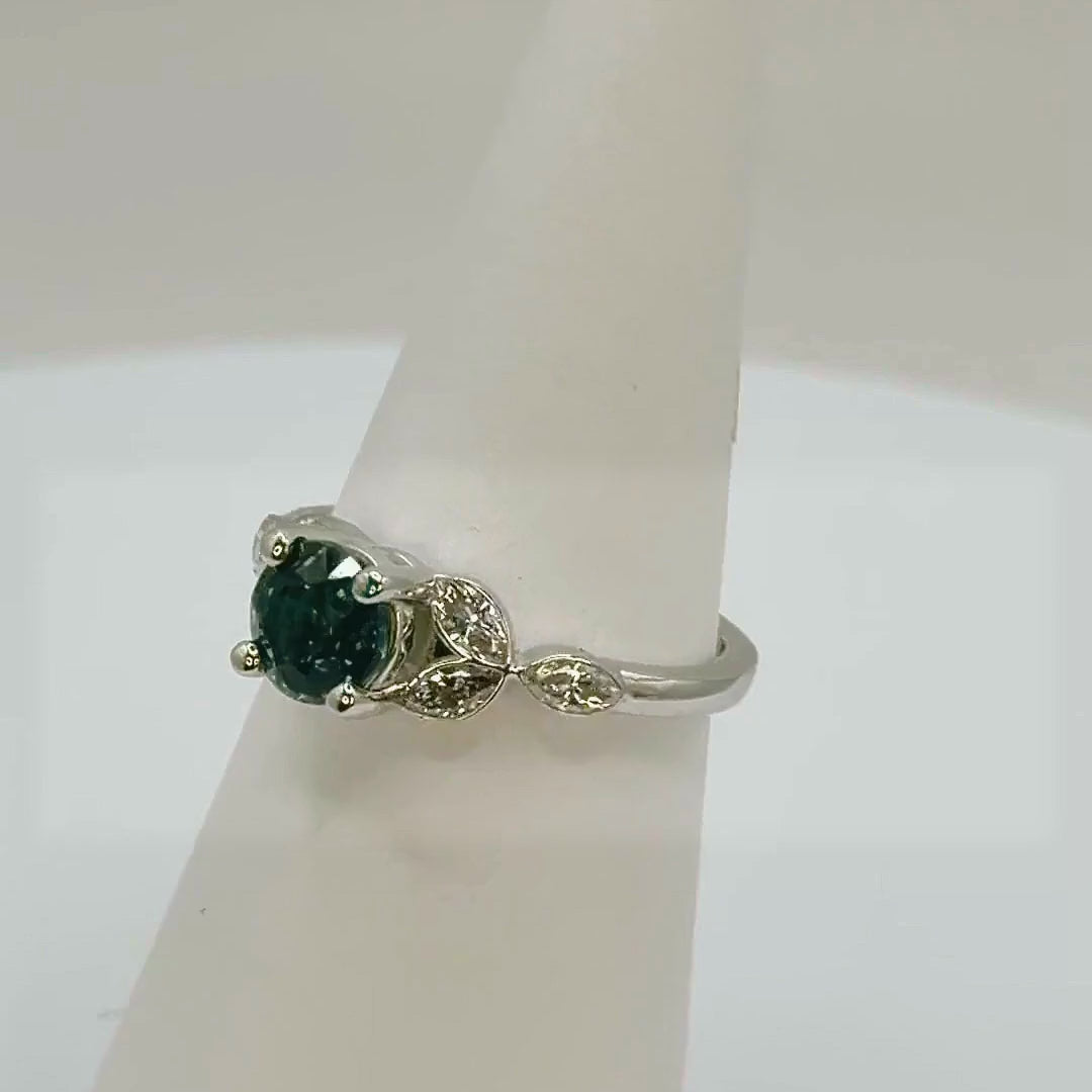 Teal sapphire platinum engagement ring rotating to show the marquise diamond shoulders