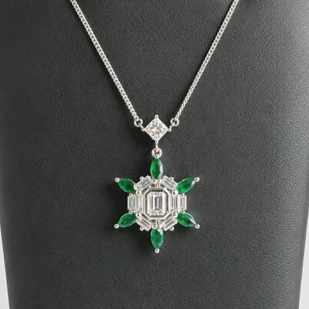 Platinum pendant with an emerald cut diamond and marquise emeralds rotating to show the floral motif