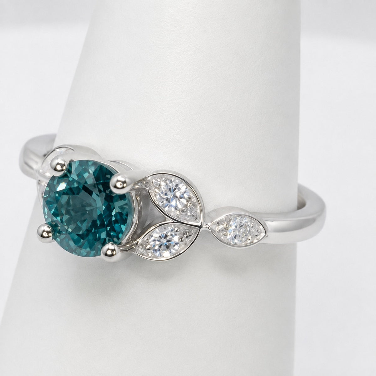 Teal sapphire engagement ring in platinum with marquise cut diamond shoulders