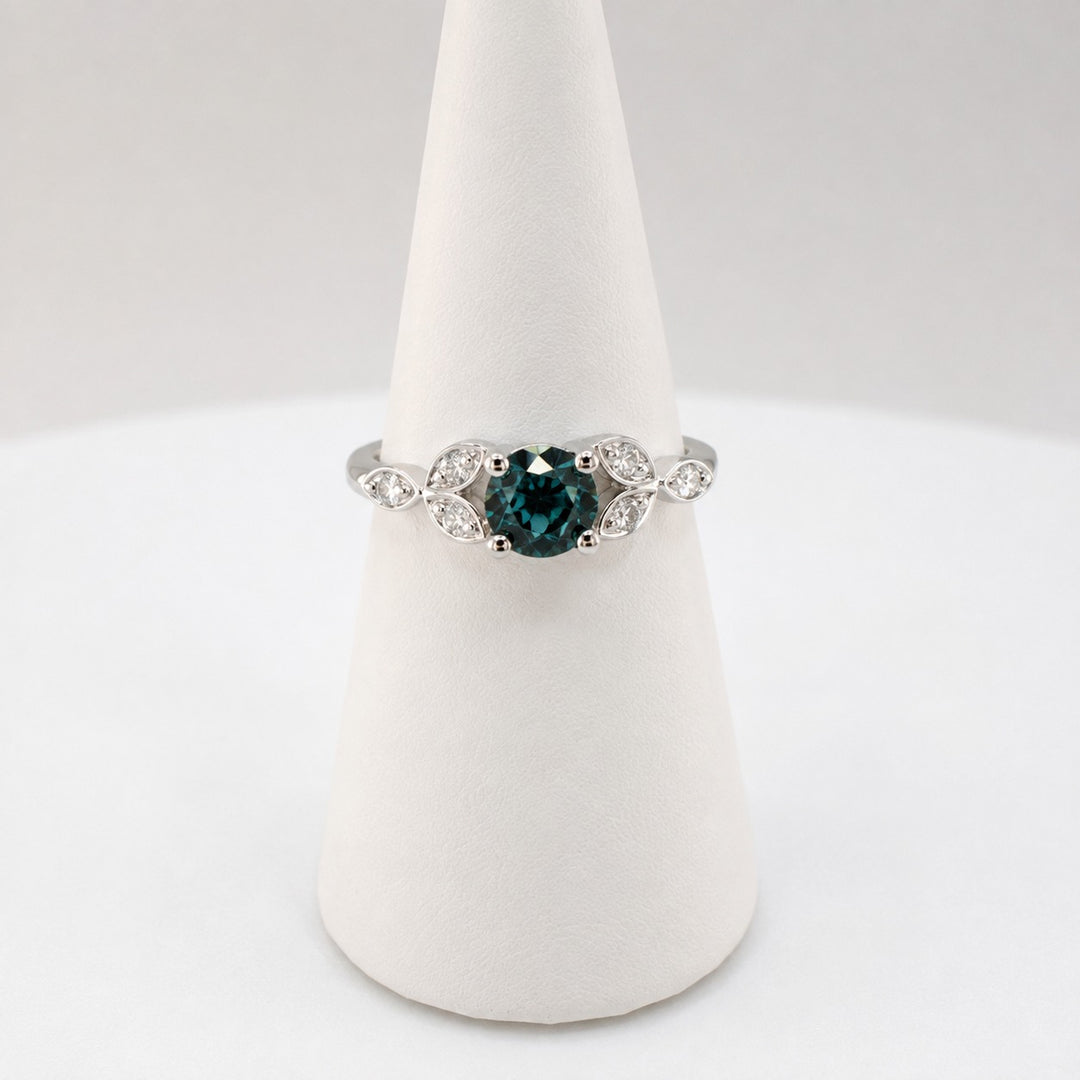 Teal sapphire ring with six marquise cut diamonds set along the shoulders